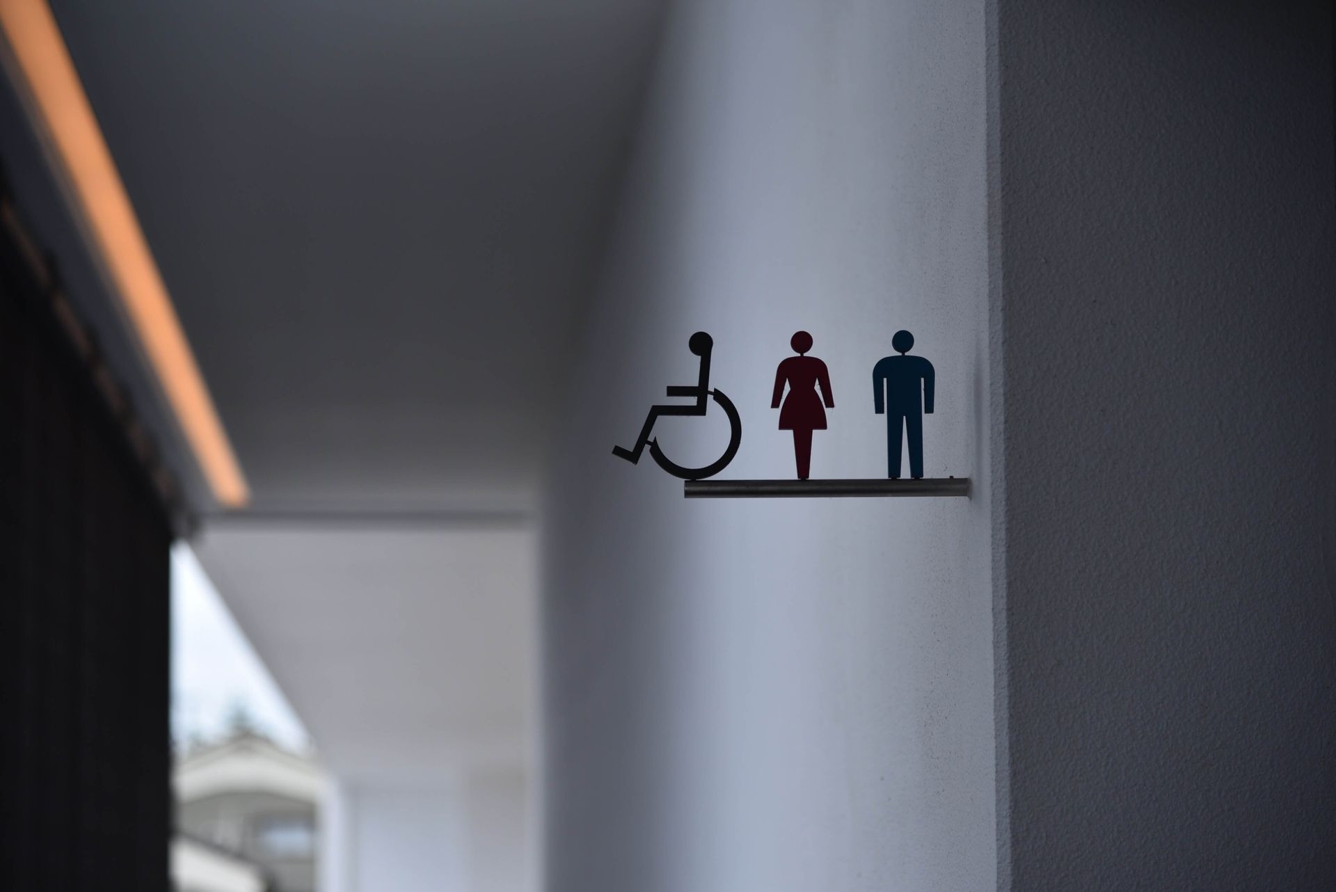 Un panneau sur un mur montre une personne handicapée, un homme et une femme