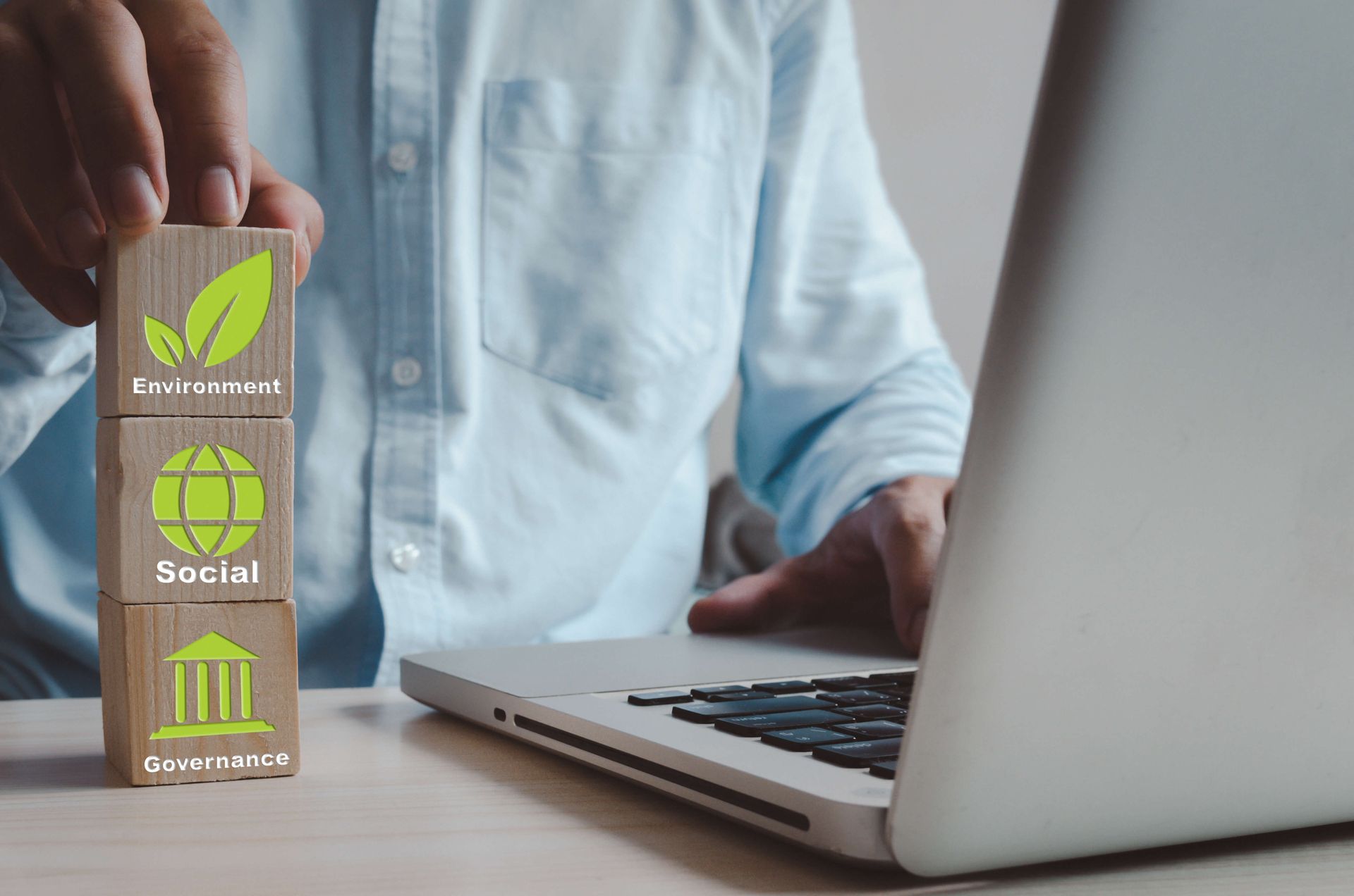 Un homme utilise un ordinateur portable et empile des blocs de bois avec des icônes vertes dessus