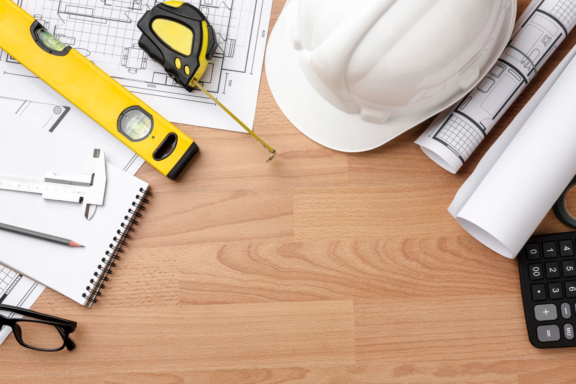 Un casque de sécurité est posé sur une table en bois à côté d'un ruban à mesurer