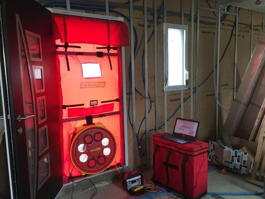 Une pièce avec une porte rouge et un ordinateur portable sur une table.