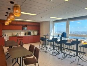 Une cuisine avec tables et chaises et une grande fenêtre.