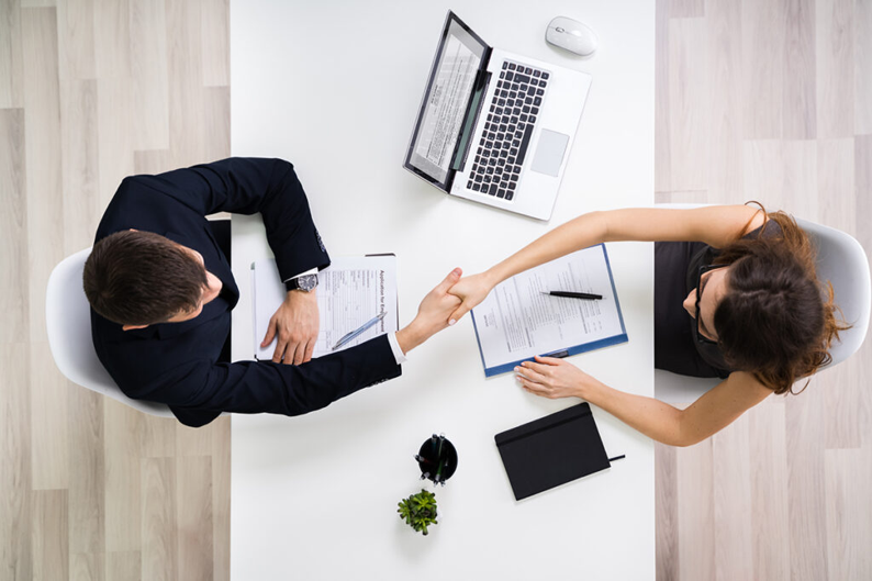 Un homme et une femme se serrent la main à un bureau