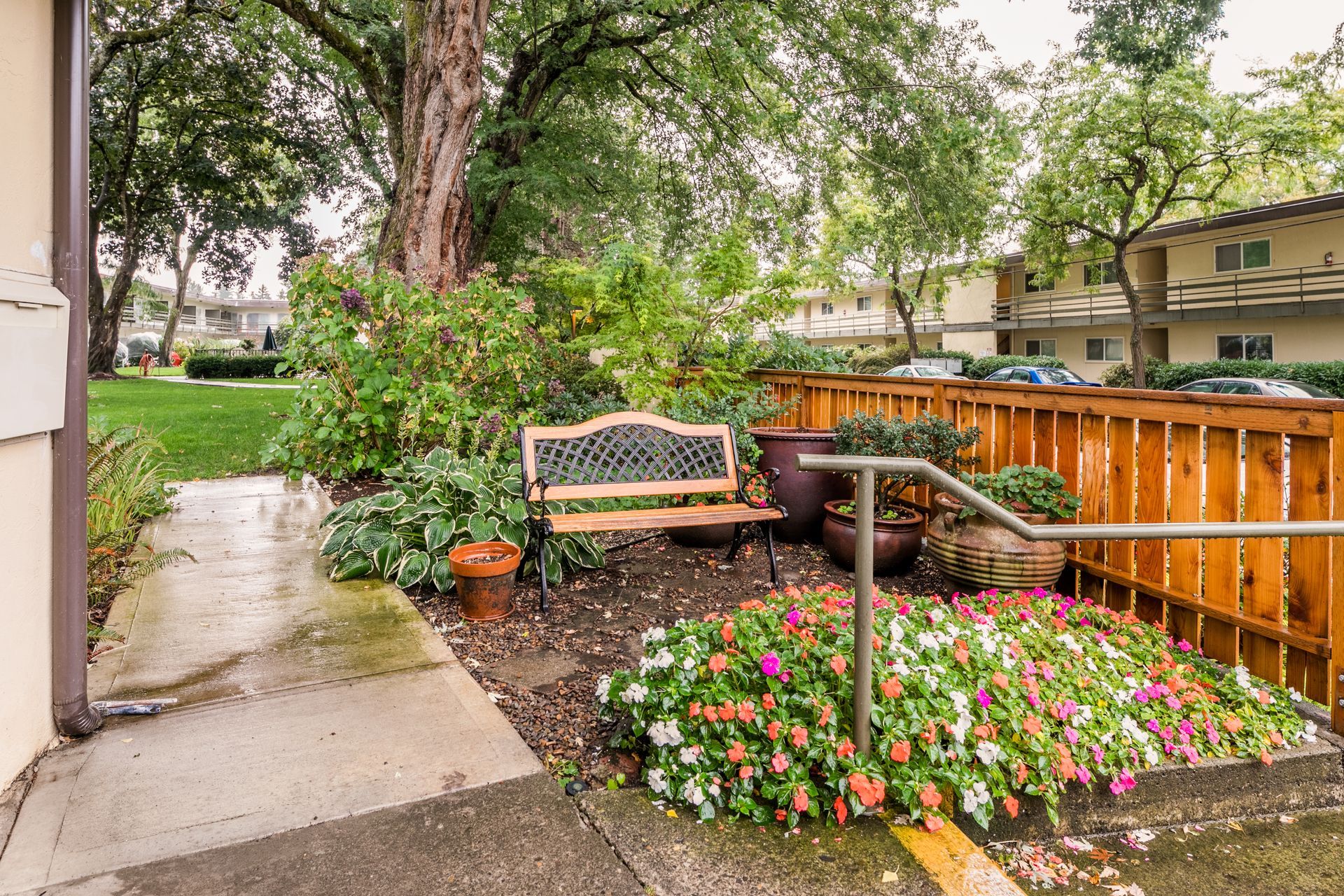 A wooden bench is sitting in a garden next to a wooden fence.