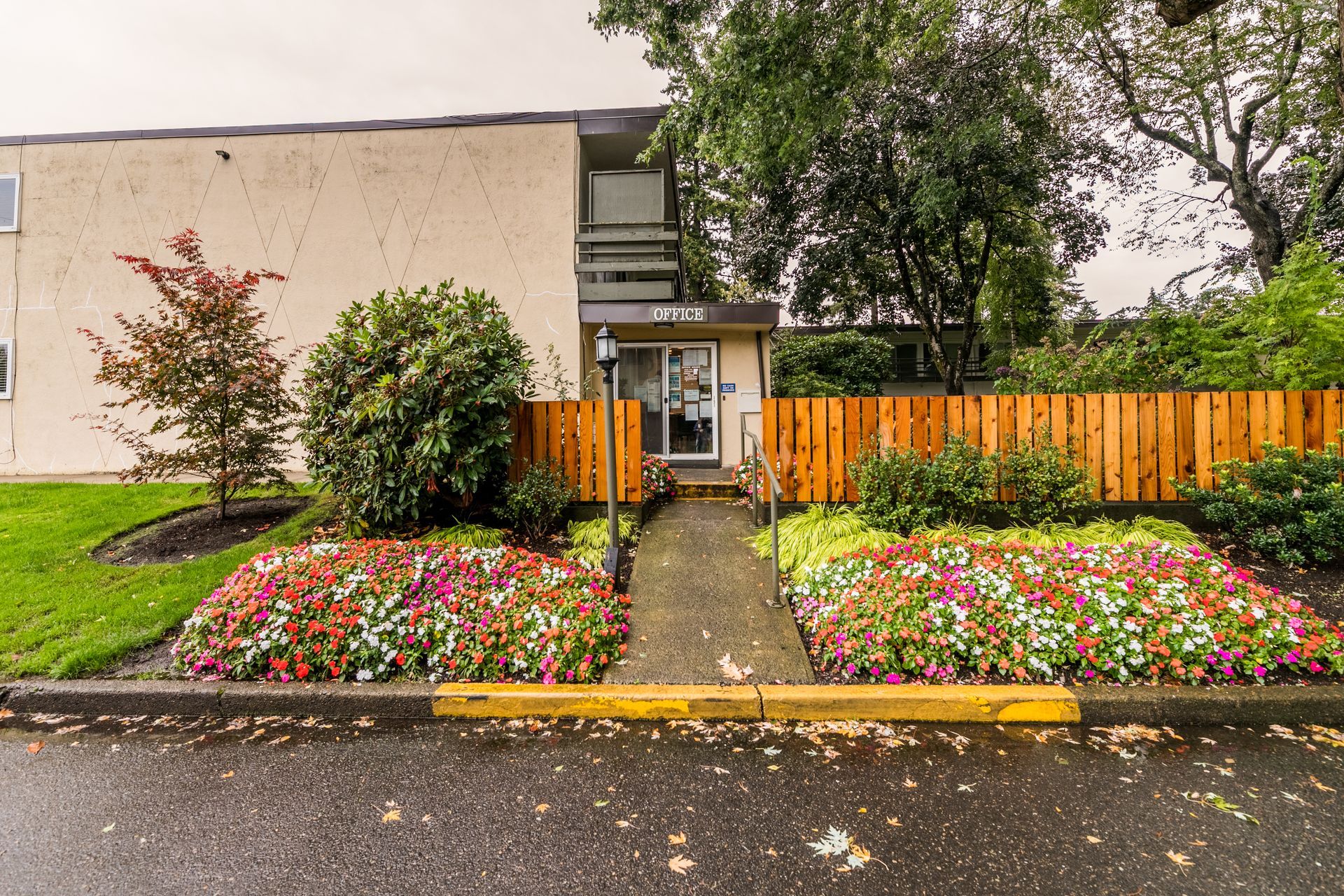 A building with a wooden fence and flowers in front of it.