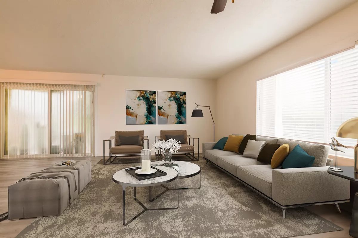 A living room with a couch , chairs , coffee tables and a ceiling fan.