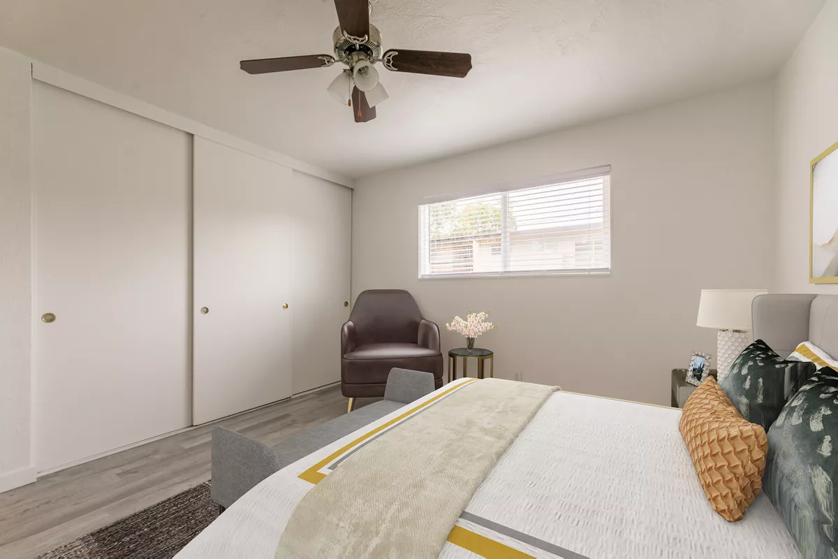 A bedroom with a bed , chair and ceiling fan.