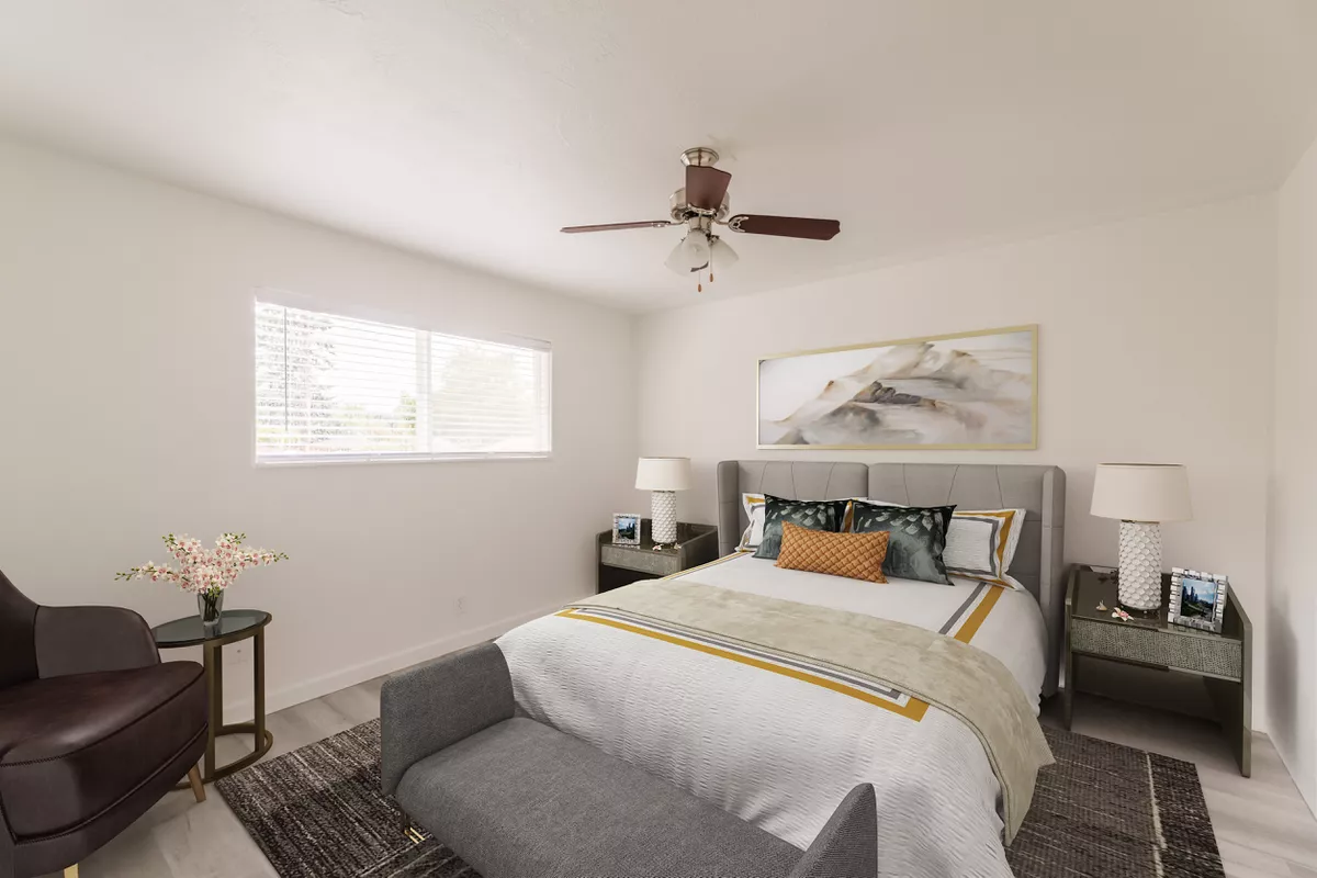 A bedroom with a bed , chair , nightstand and ceiling fan.