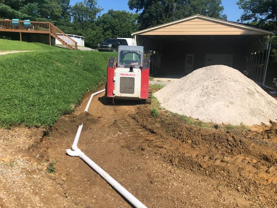 A bulldozer is driving down a dirt road next to a pile of dirt.