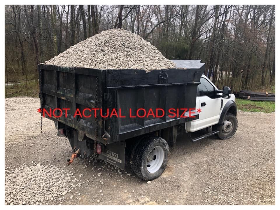 A dump truck filled with gravel is parked in a dirt lot.