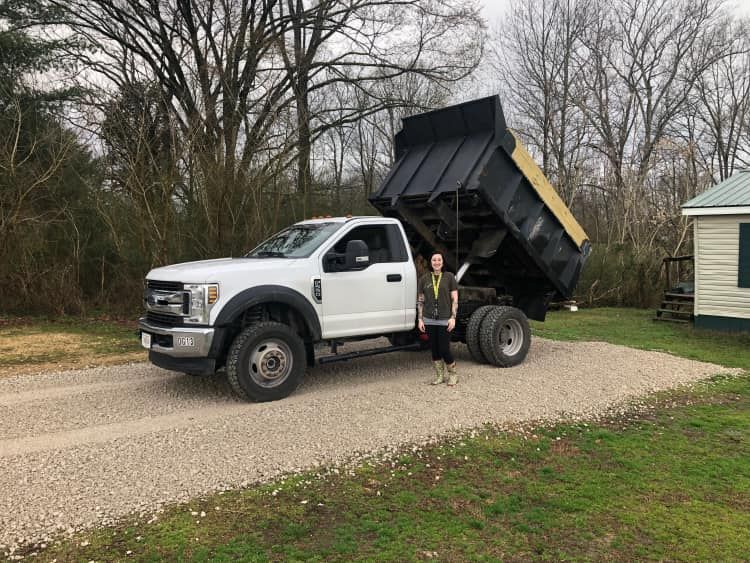 A man is standing in front of a dump truck.