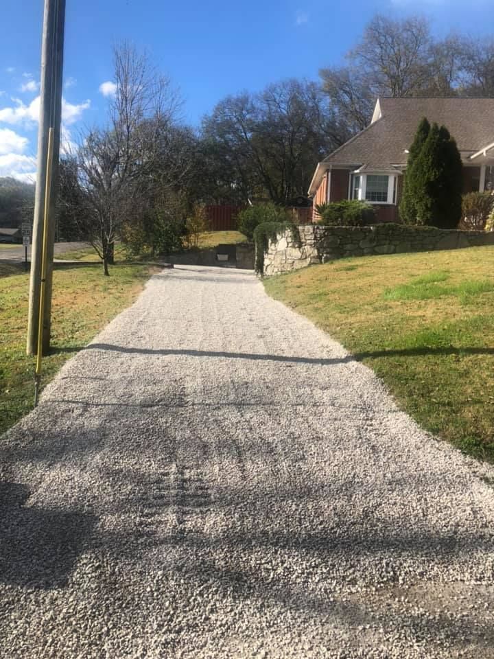 A gravel driveway leading to a house on a sunny day.