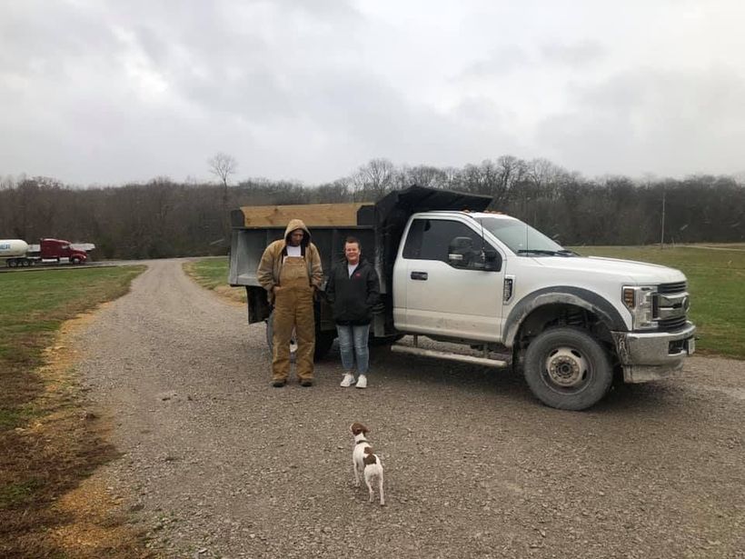 A man and a woman are standing next to a dump truck.