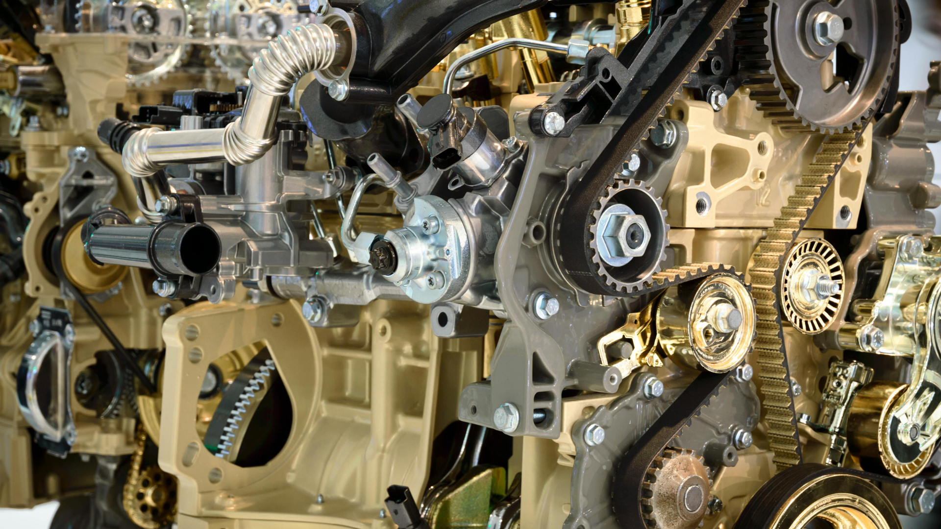 A close-up view of a complex industrial engine, highlighting gear systems, a timing belt, and metal components.