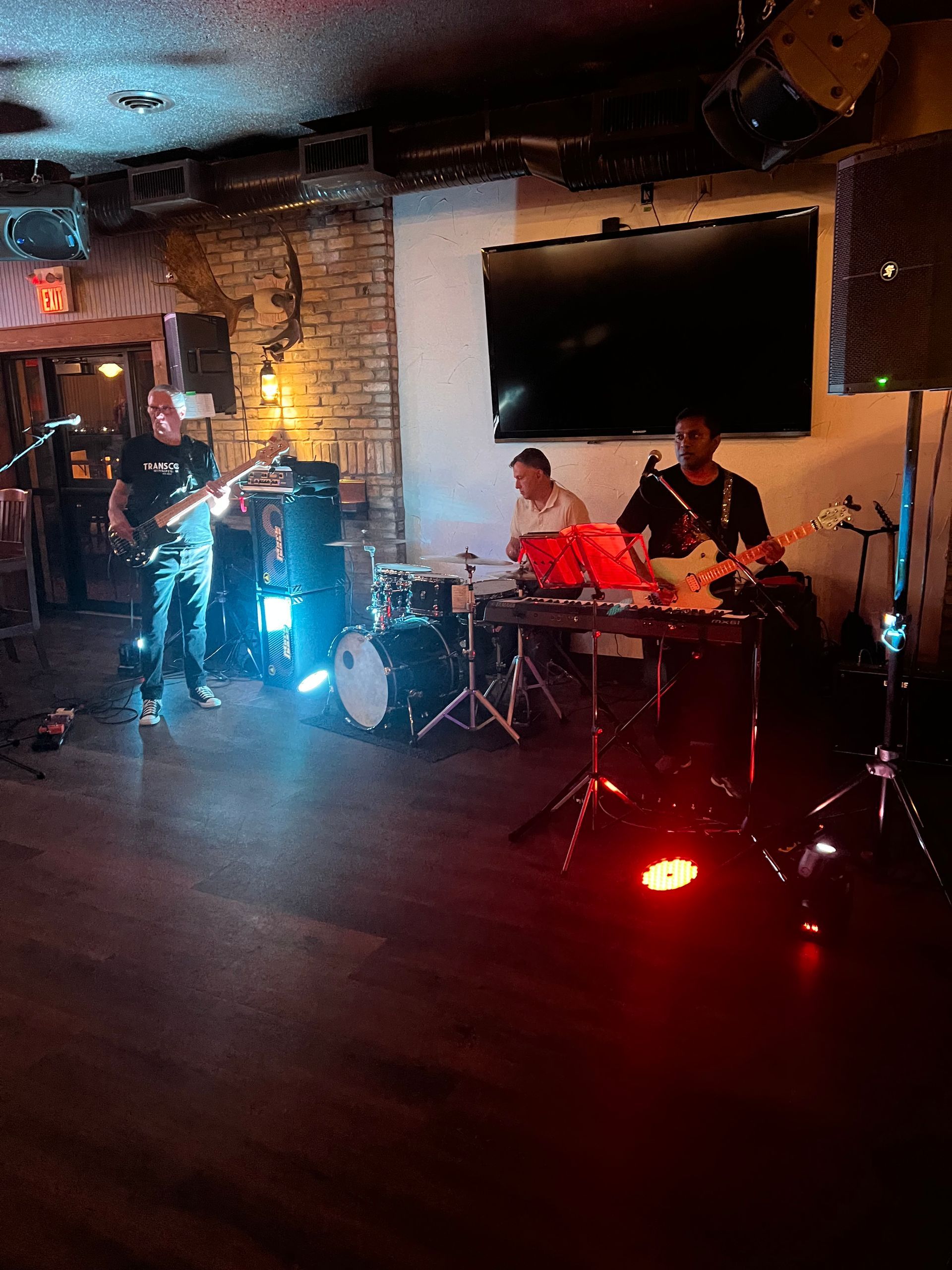 Band performs on stage in a crowded venue lit by spotlights, with 