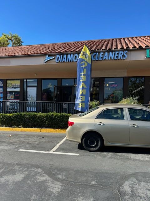 A storefront for Diamond Cleaners, with a gold car parked in front.