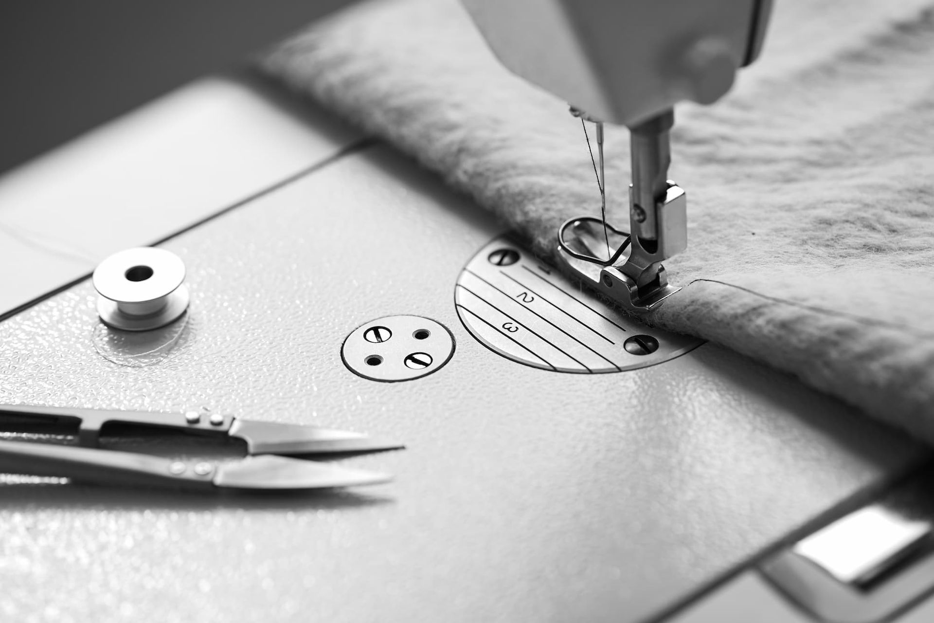 Sewing machine stitching gray fabric.
