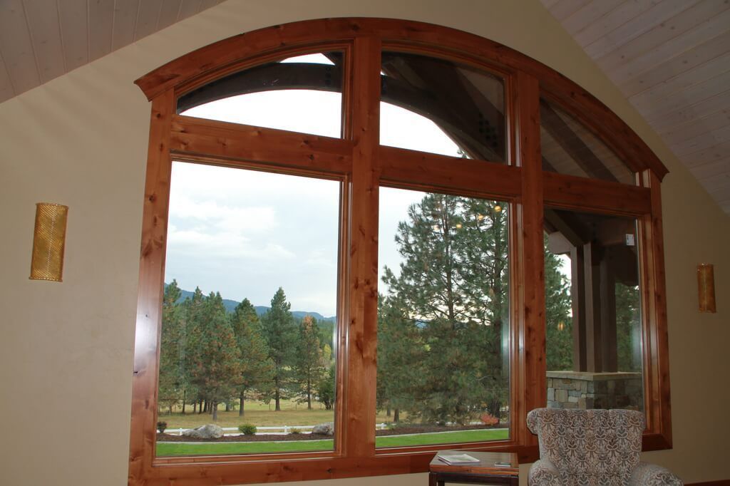 A living room with a large window looking out to a forest