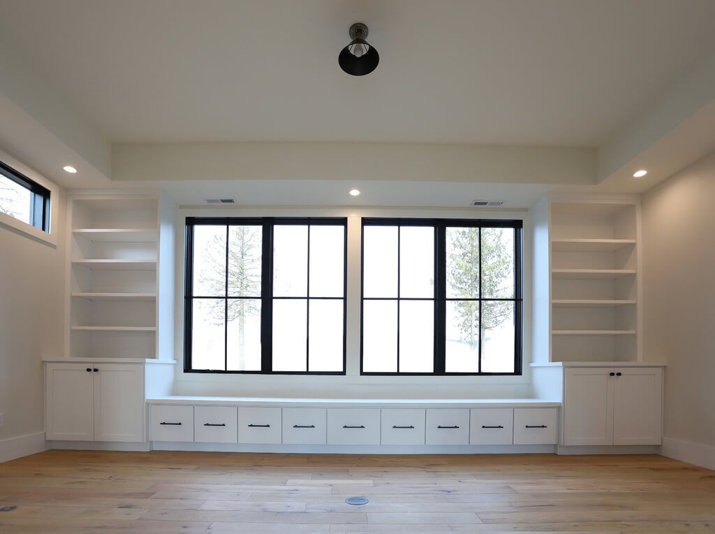 An empty room with lots of windows and shelves