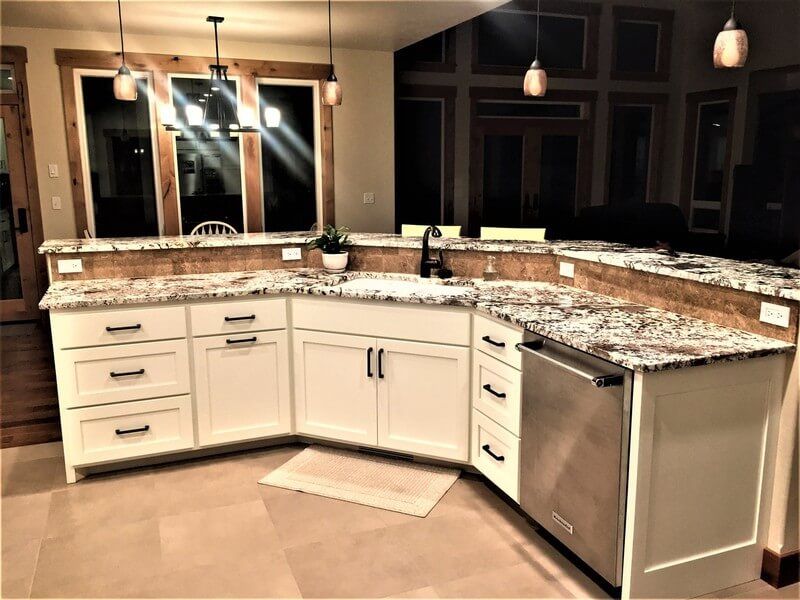 A kitchen with white cabinets and granite counter tops.