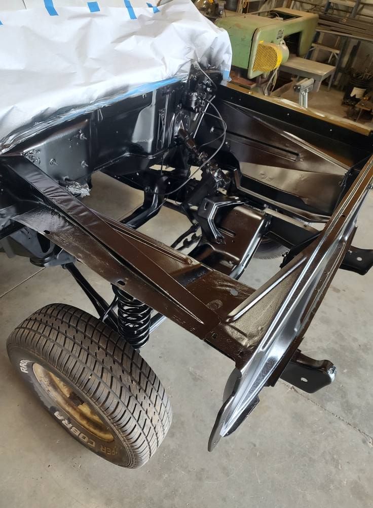 A car frame is sitting on the ground in a garage.