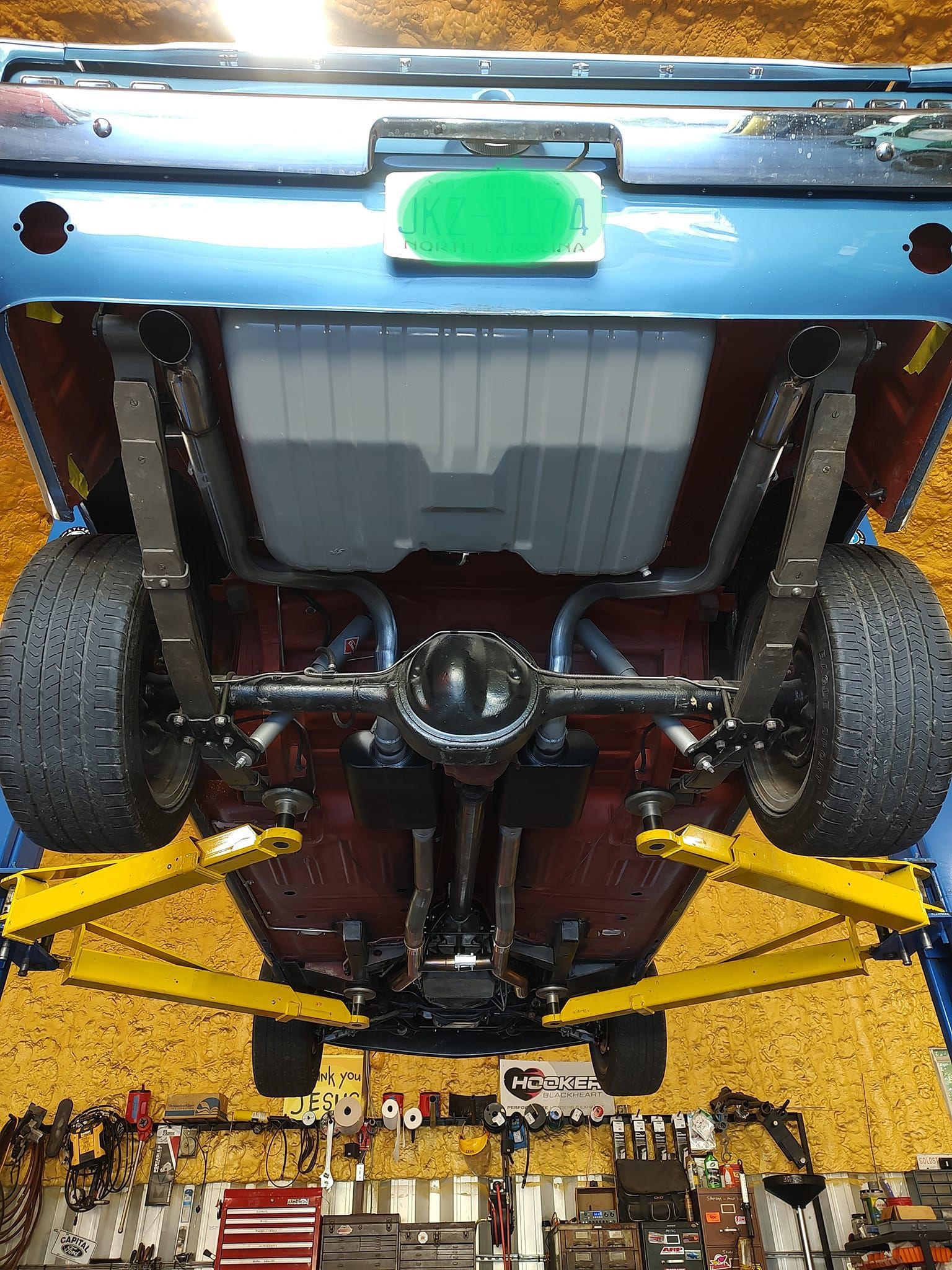 Blue classic car's underside on a lift. Fuel tank, exhaust