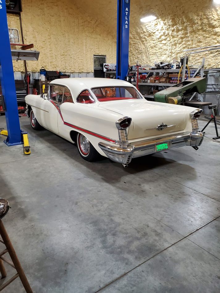 Cream-colored vintage Oldsmobile in a garage setting. 