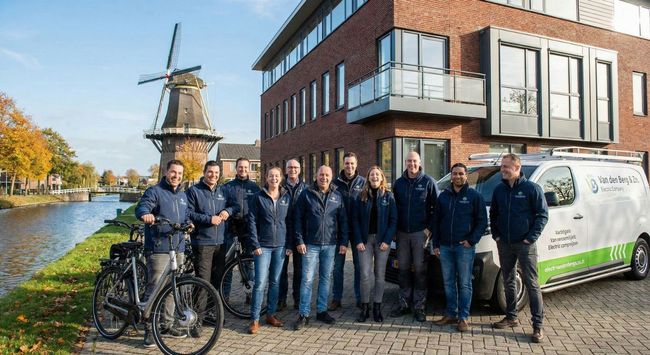 Mensen lachen en werken op kantoor. Een vrouw in een spijkerblouse lacht naar de camera.