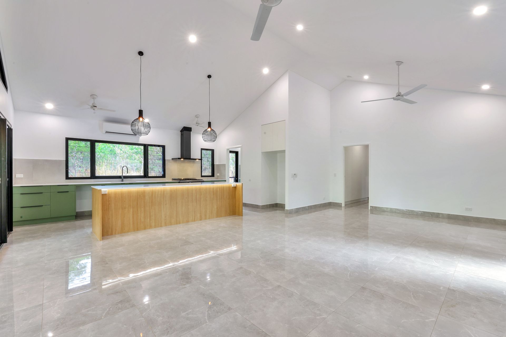 Open-concept kitchen with light wood island, green cabinets, and gray tiled floor; white walls and high ceilings — RMB Air Conditioning & Electrical in Winnellie, NT