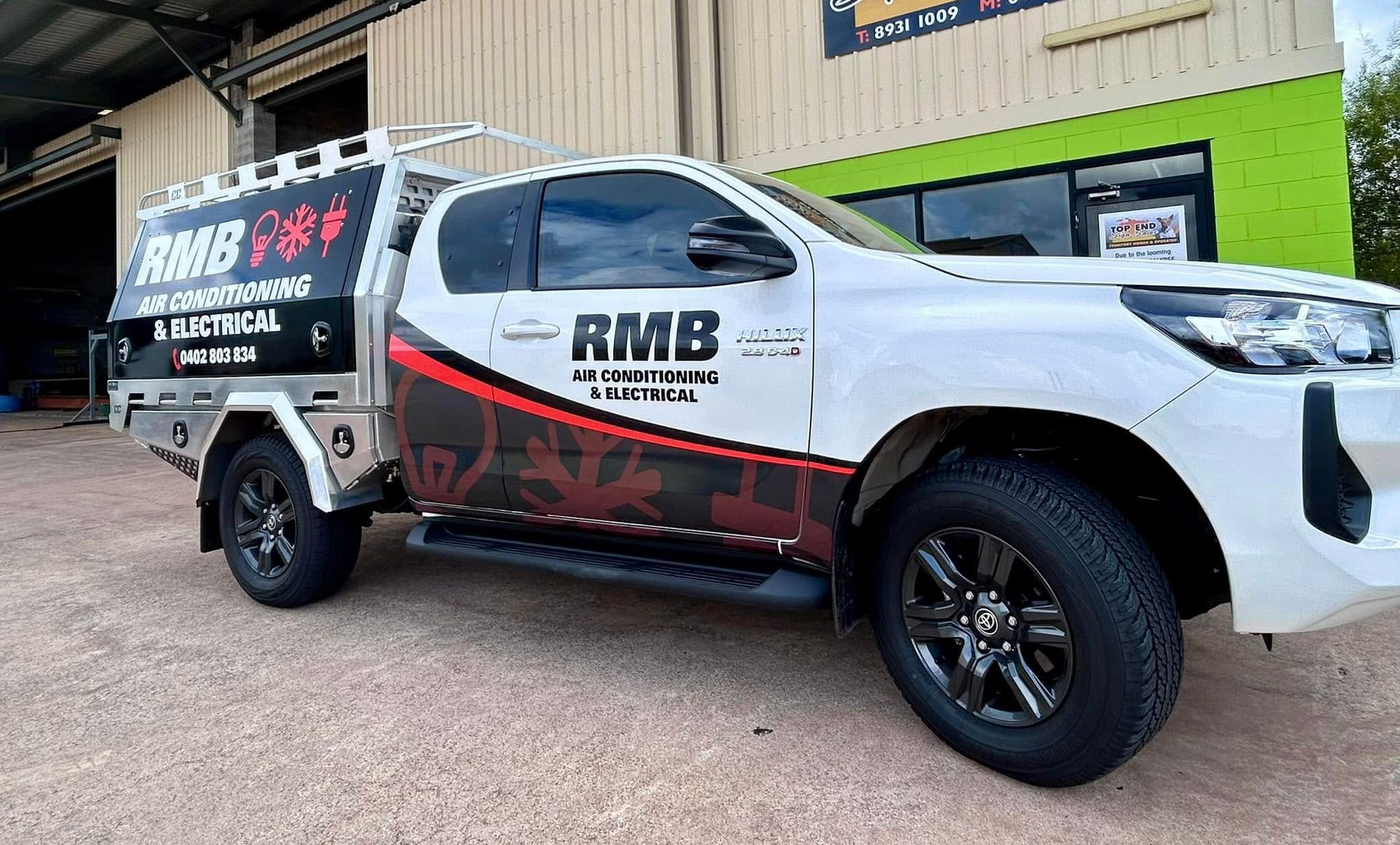 White truck with company logo on the side and back, parked outside a building — RMB Air Conditioning & Electrical in Winnellie, NT