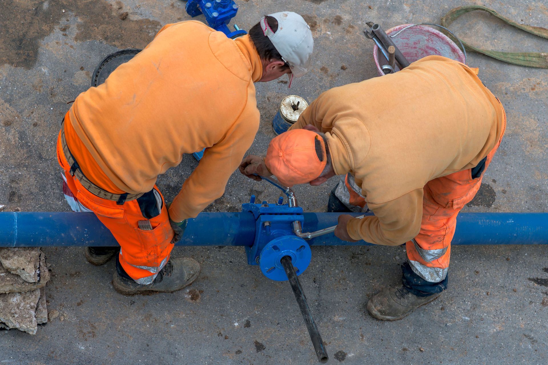 Two commercials are repairing a blue underground pipe valve. a blue underground pipe valve. Two commercials are repairing a blue underground pipe valve. a blue underground pipe valve.