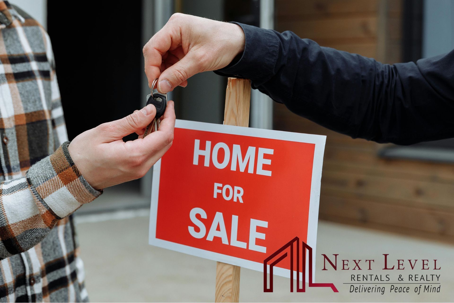 An image of e man handing house keys to another man infront of a home for sale sign