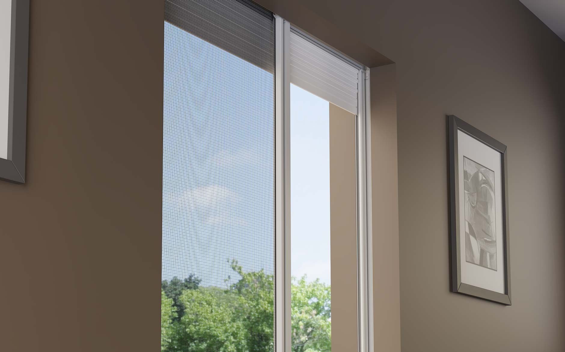 Una mano che mescola un cappuccino schiumoso in una tazza nera Mado, un croissant e dei bicchieri d'acqua su un tavolo.