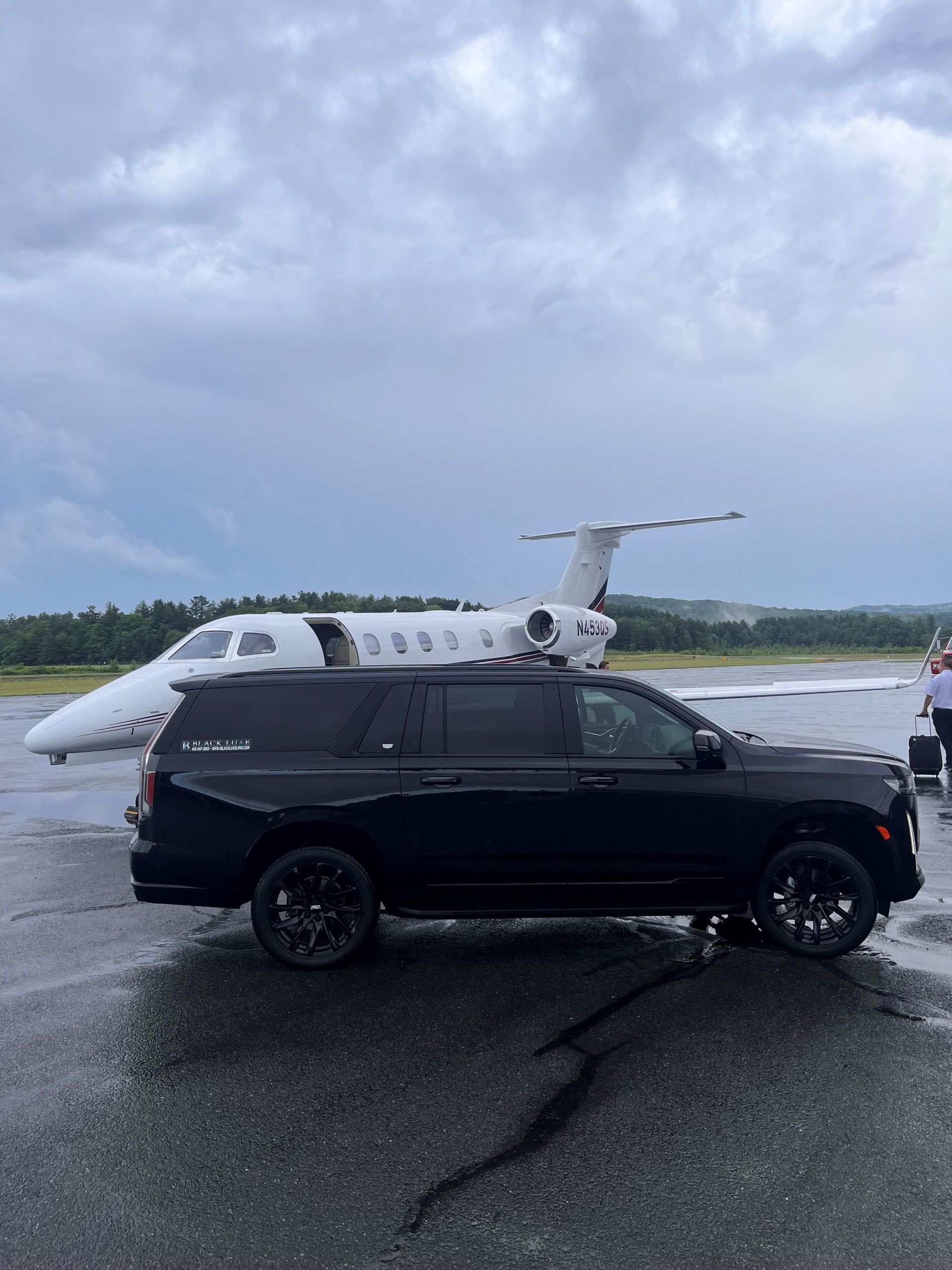 A Man With A Backpack Is Looking Out Of A Window At An Airplane Taking Off — Pittsfield, MA — Black Luxe Luxury Car
