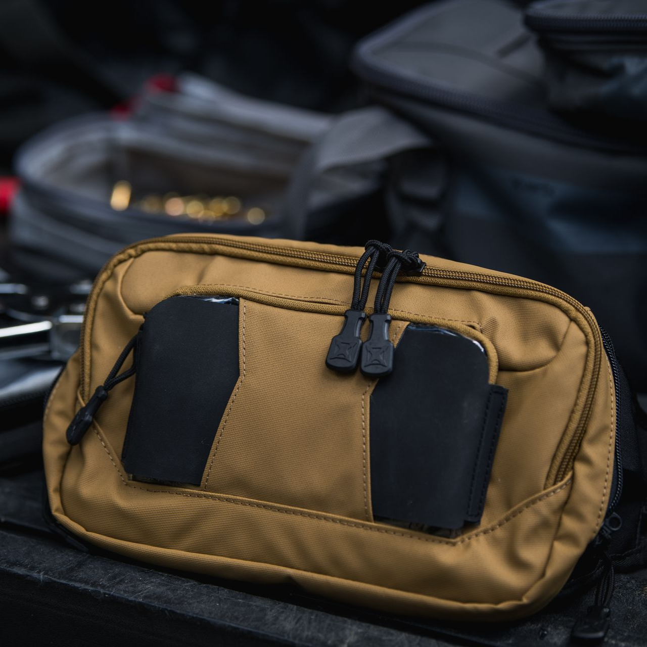 Tan, rectangular, zippered tactical pouch with two black rubberized panel accents on its front.