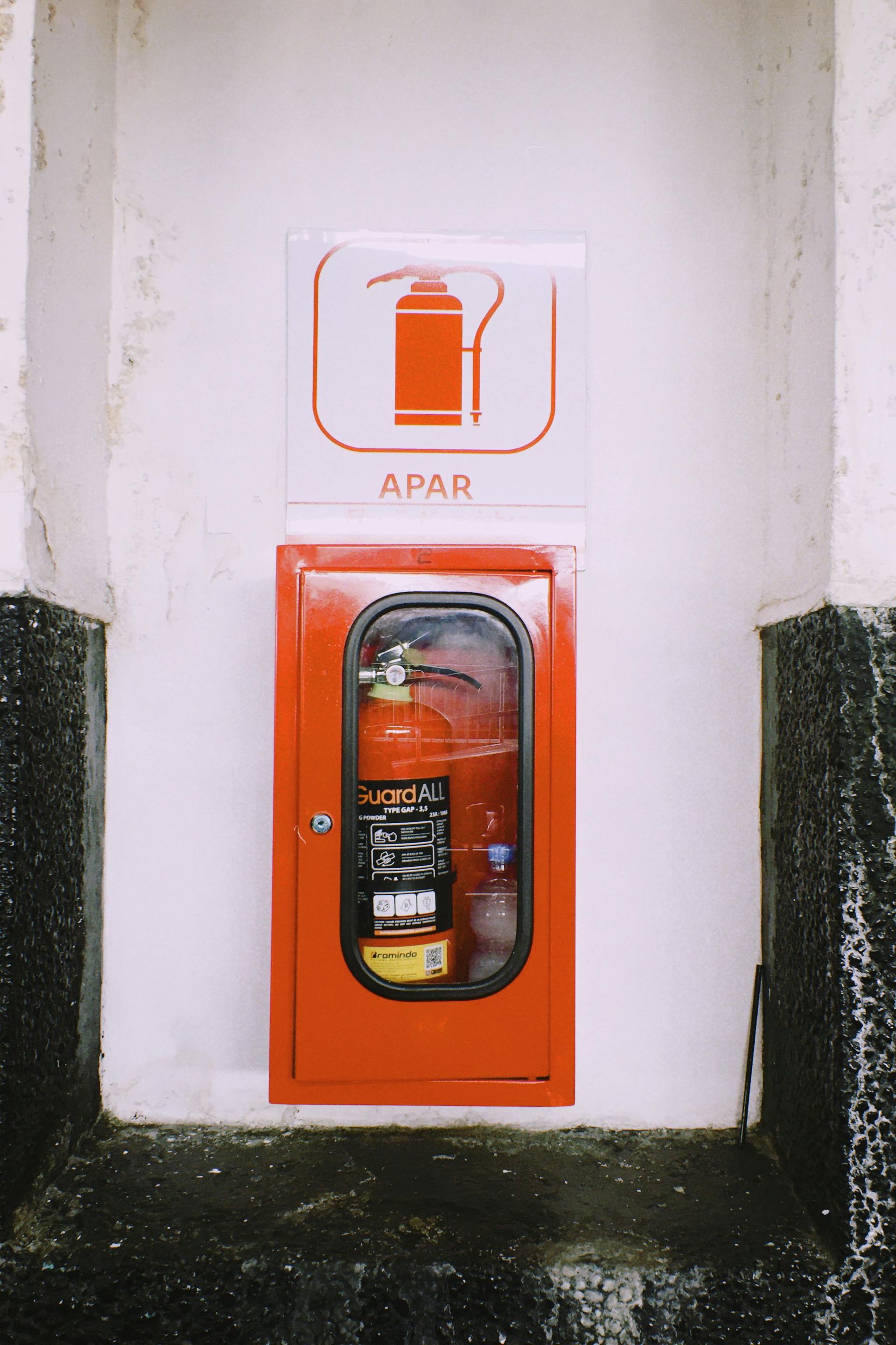 A fire extinguisher inside a red wall-mounted cabinet, with an 