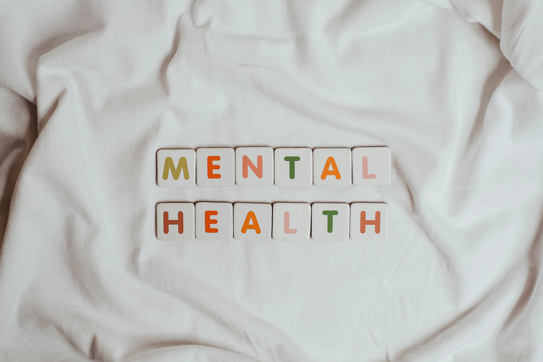MENTAL HEALTH spelled with letter tiles on a rumpled white fabric background
