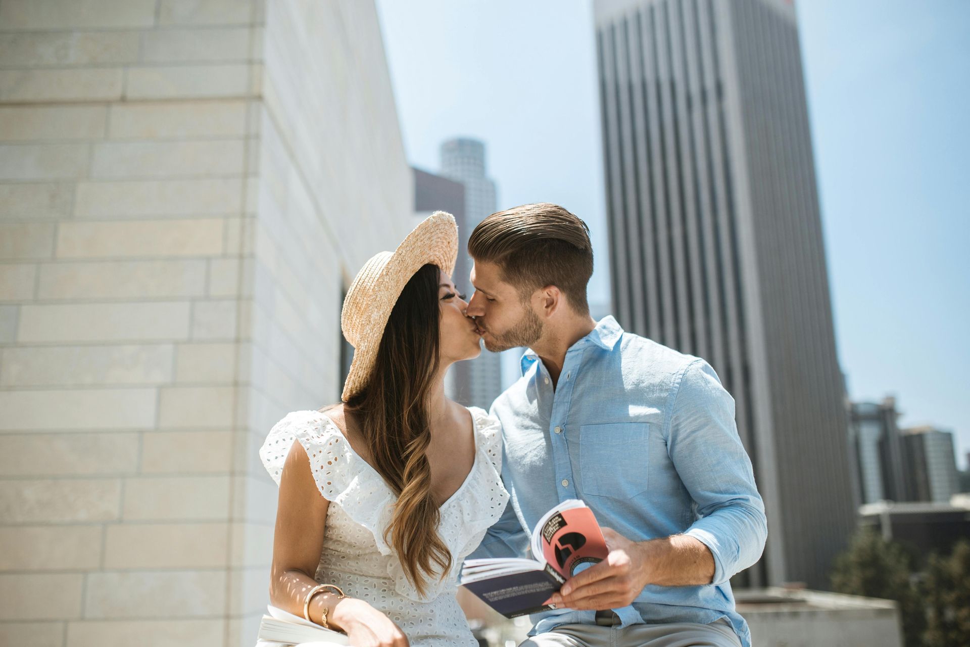 A man and a woman are kissing in front of a city skyline.