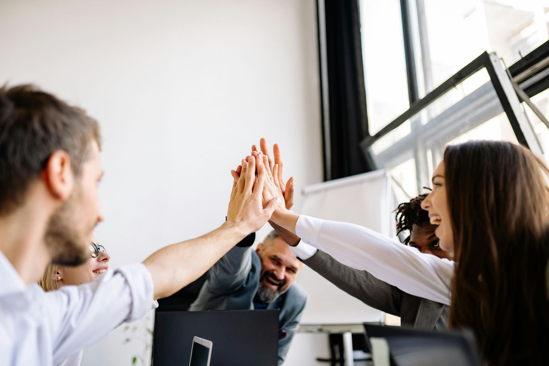 A group of people are giving each other a high five in an office.