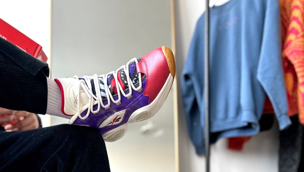 A person wearing a pair of colorful sneakers is sitting in front of a mirror.