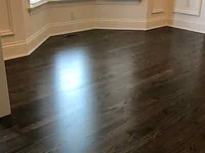 A dark wooden floor in a room with a window.