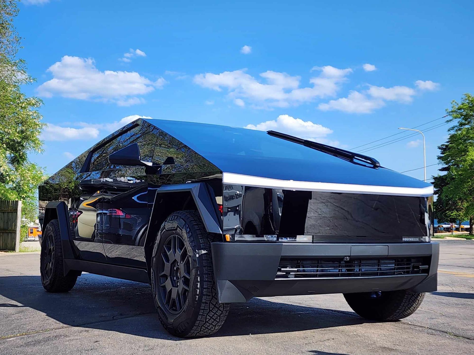A black tesla cybertruck is parked on the side of the road.