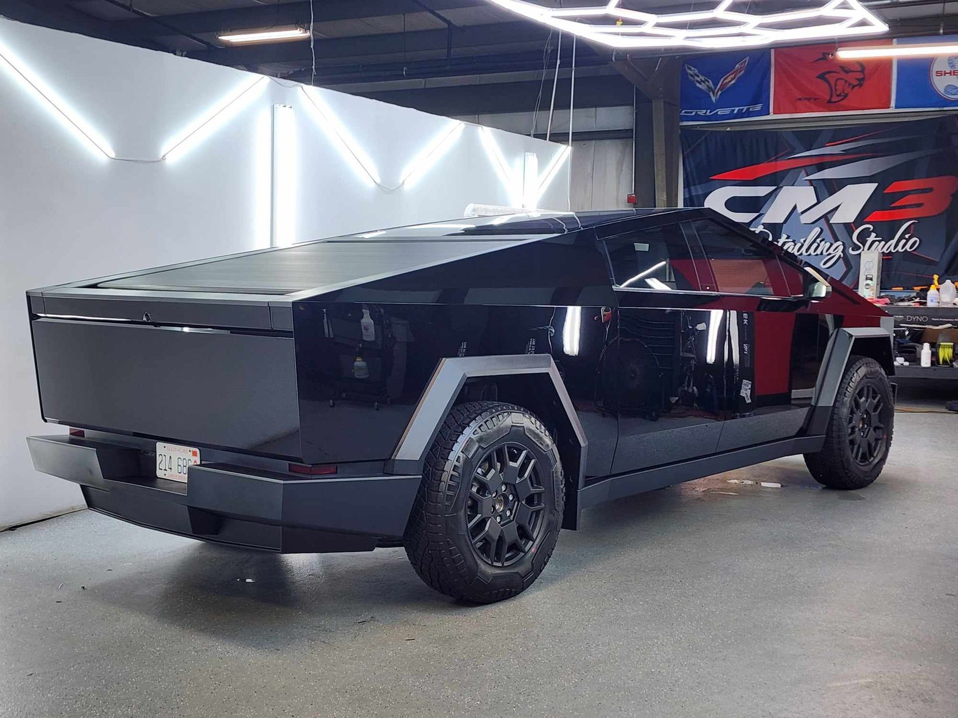 A black truck is parked in a garage next to a sign that says cm3