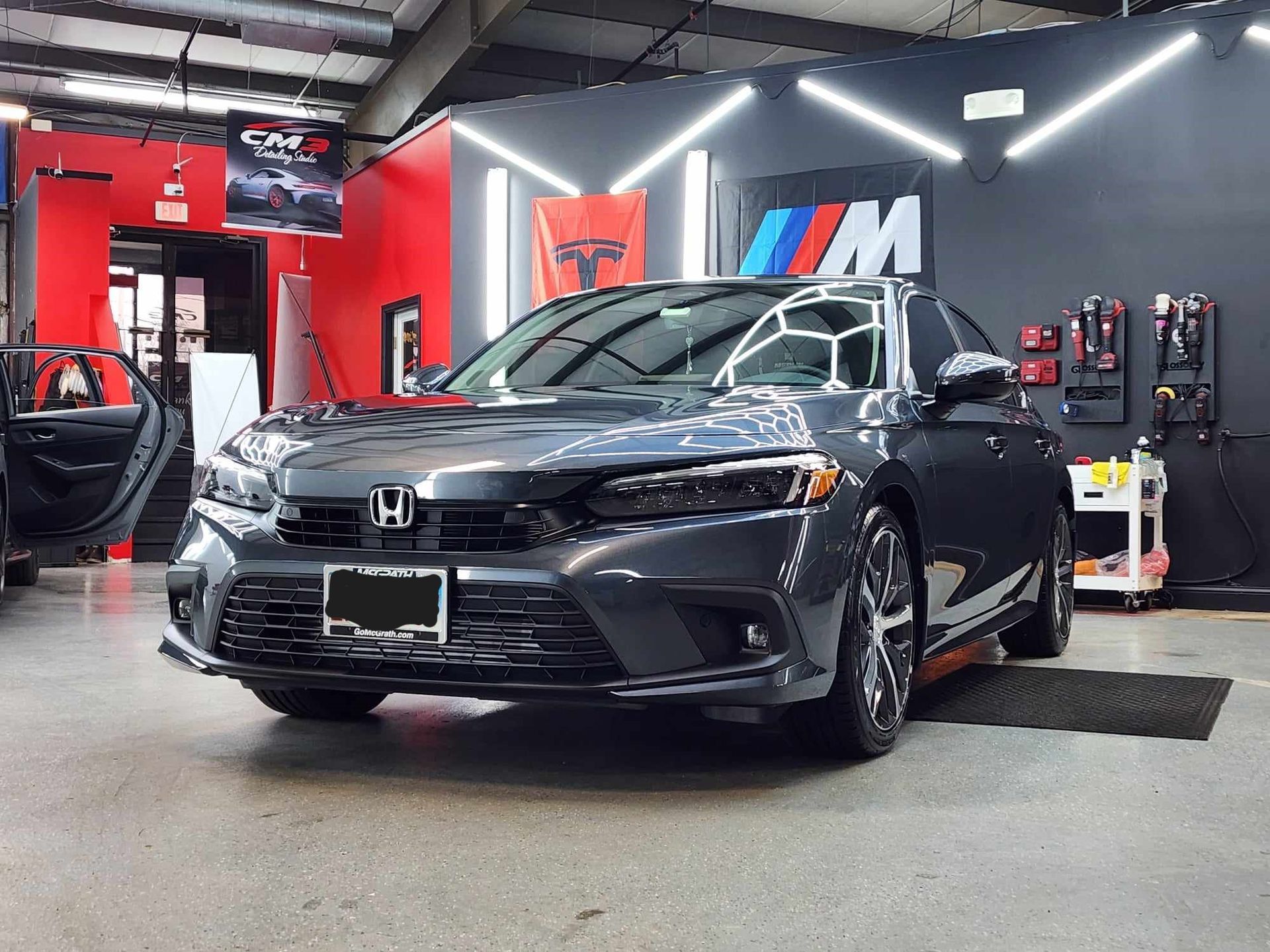 A gray honda civic is parked in a garage.