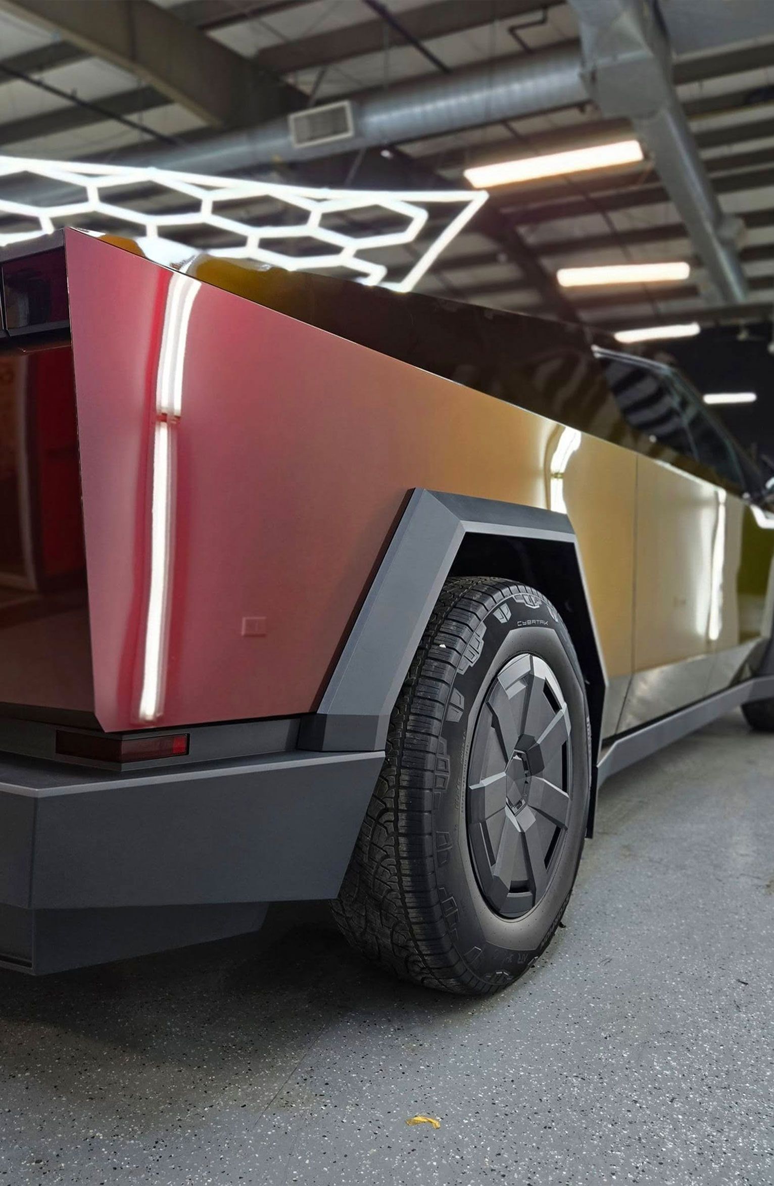 Gray sports car covered in foam being washed at a car wash facility.