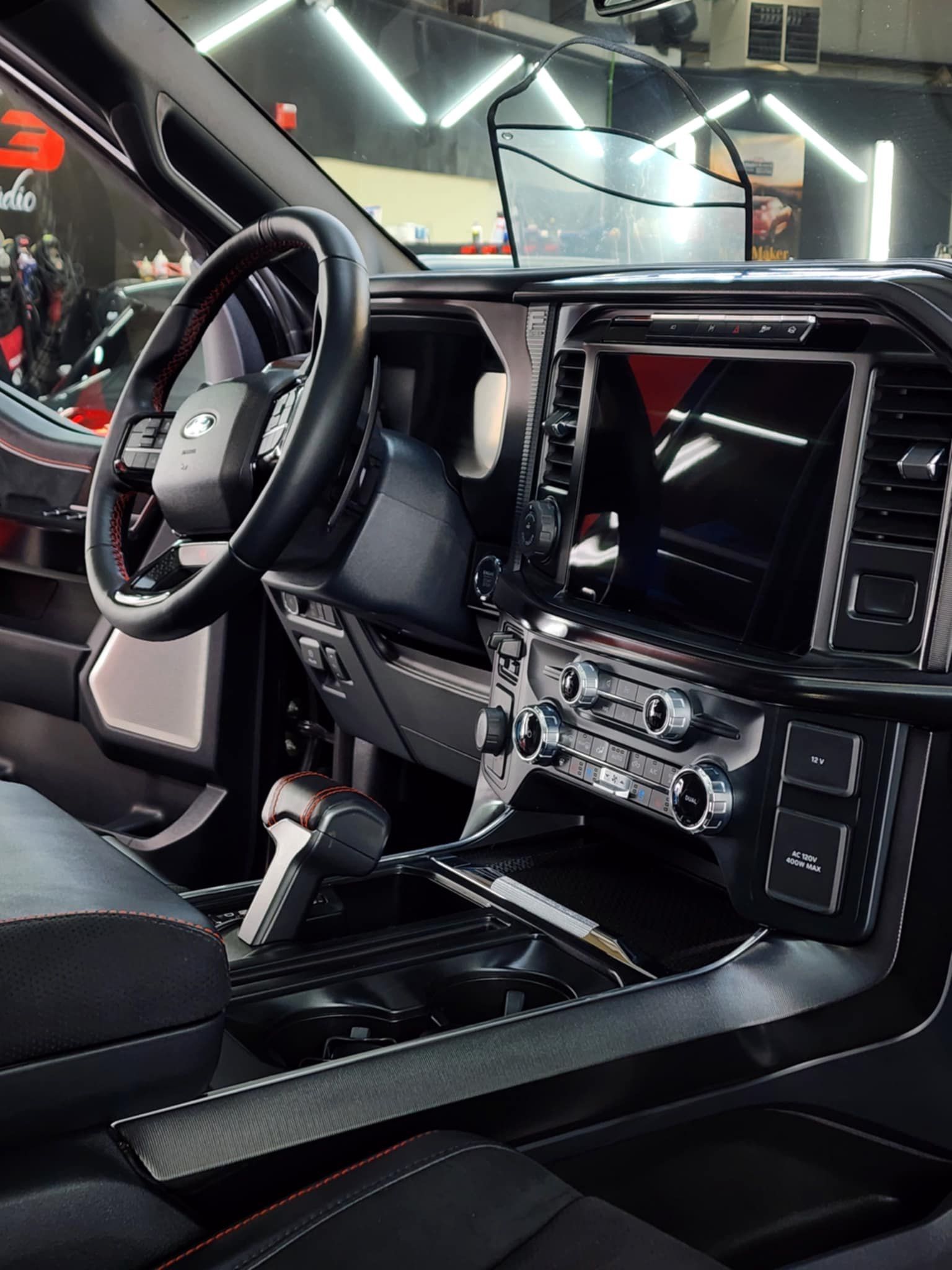 Interior view of a black Ford truck with a large touchscreen display and black leather seats.