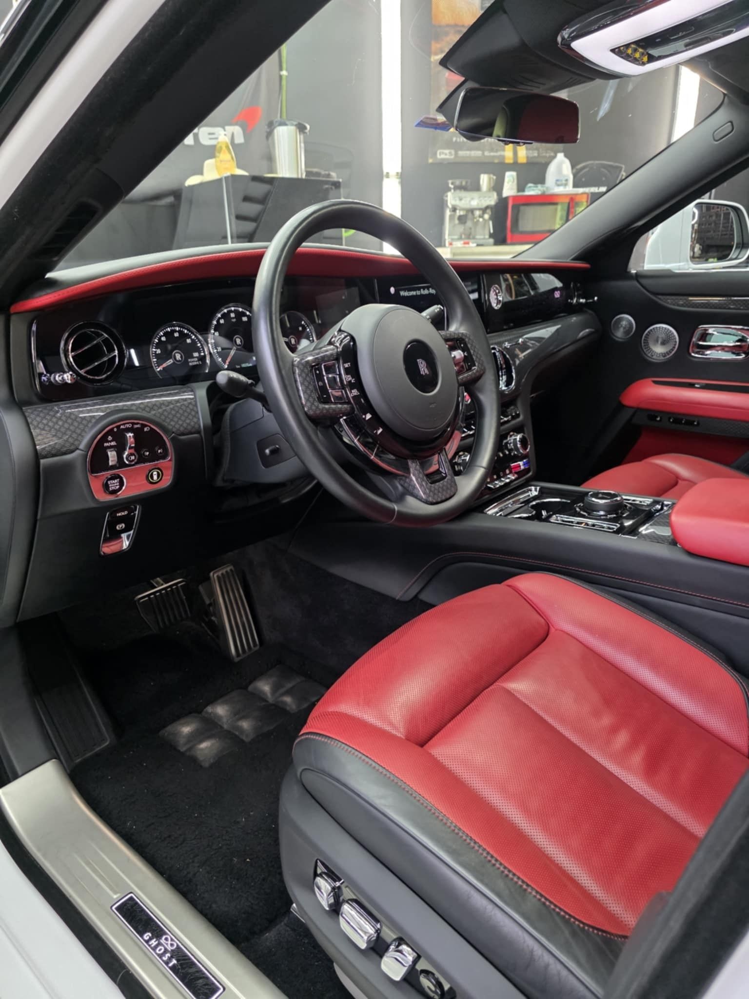 Luxury car interior: red leather seats, black dashboard, chrome accents, steering wheel, and door panel.