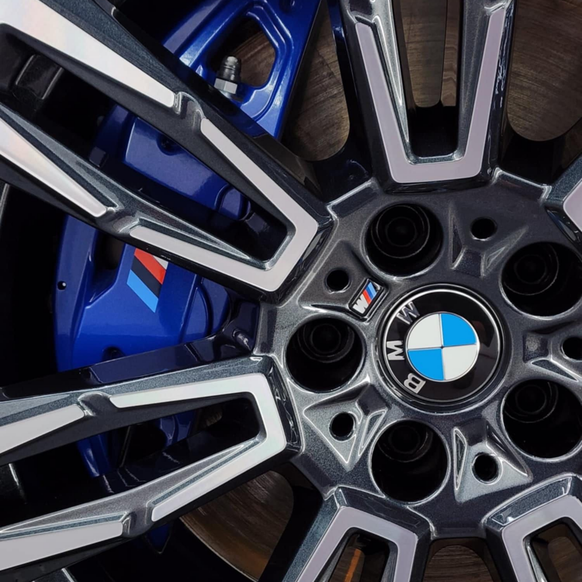 Blue Ford Mustang Shelby GT350 with white stripes, parked in a car detailing shop, with a pickup truck in the background.