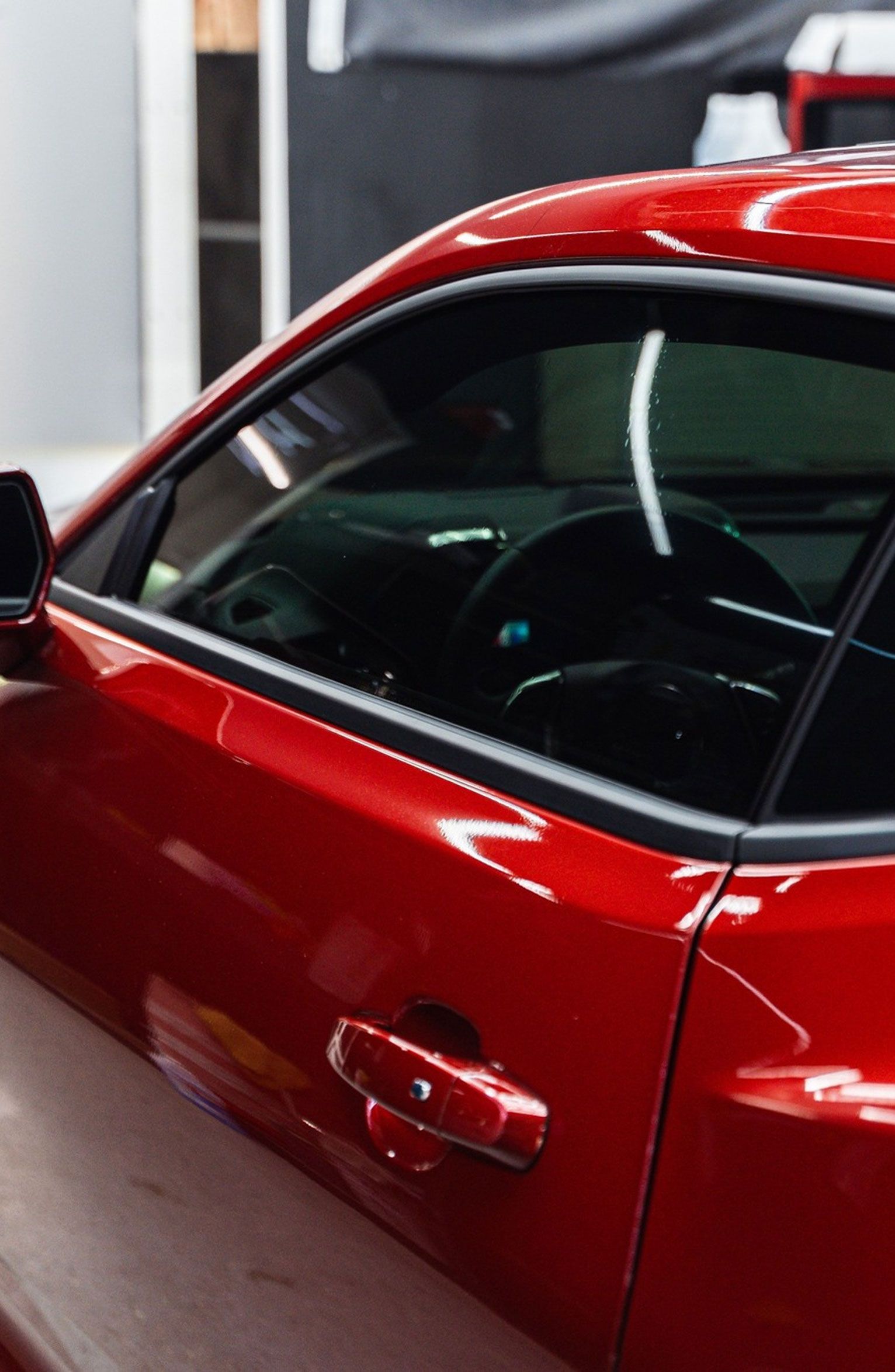 Red sports car, close-up, focusing on the door, window, and interior. Shiny finish, black tint.