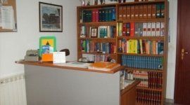 una scrivania e dietro una libreria