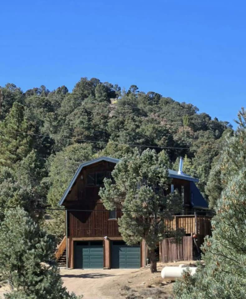 A house in the middle of a forest with a blue sky in the background